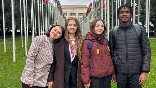 Some of the youth advocates posing in front of the alley of flags of the Palais des Nations in Geneva